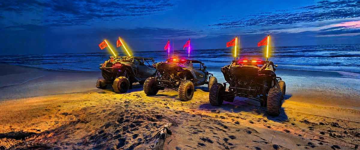 Three UTVs from behind on a beach at blue hour, chase lights and LED whips glowing